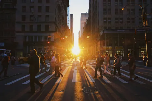 People cross a road as a sunset shines through buildings in the background. Salesforce is sunsetting startup Clockwise